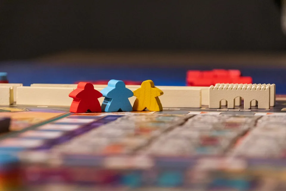Rote, blaue und gelbe Holzfiguren auf einem Spielbrett